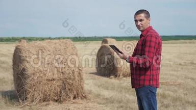 智慧农业理念.. 一名农民工人在数字平板电脑上的田野里研究干草堆。 慢速视频